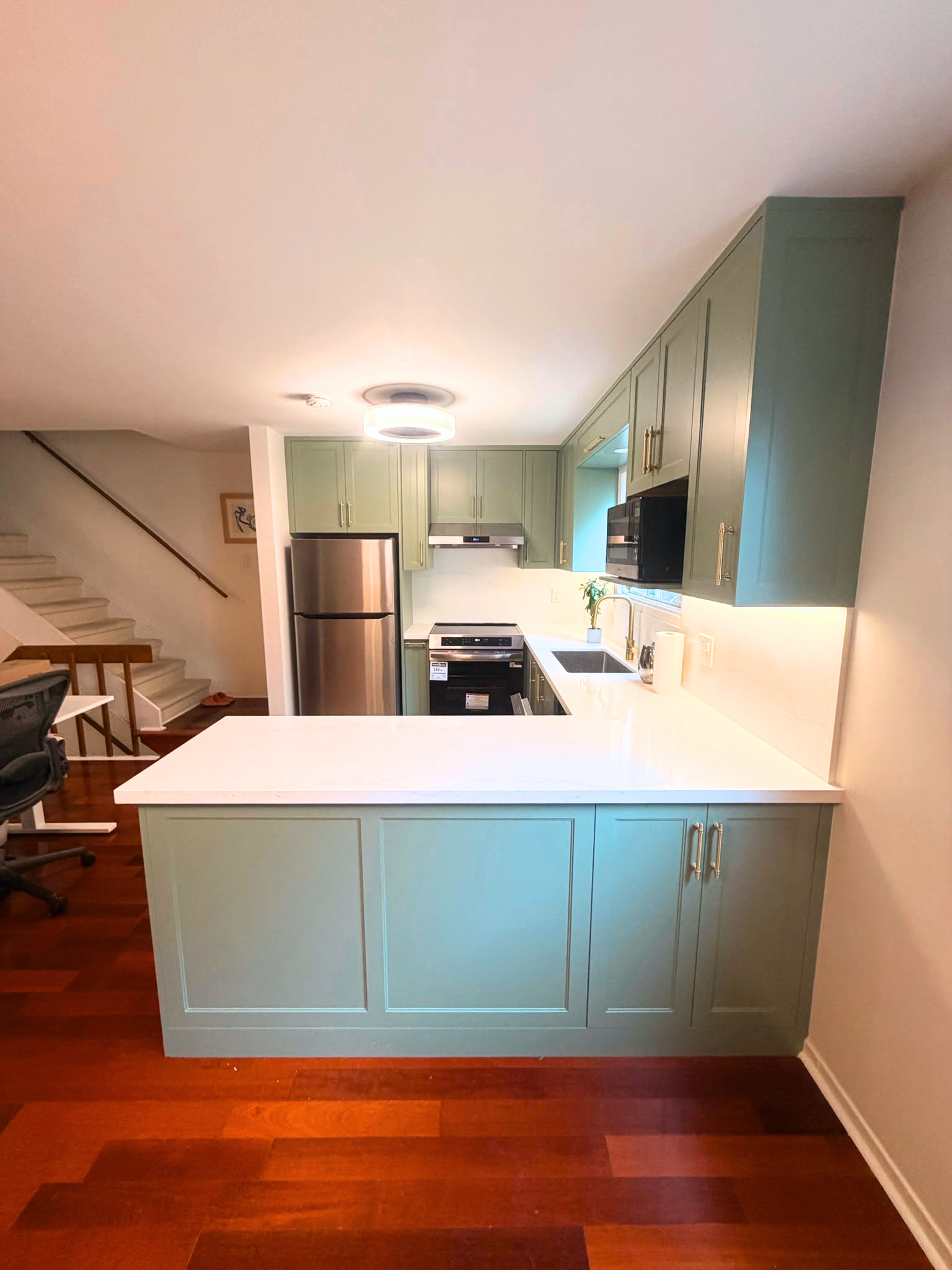 North York kitchen renovation peninsula and staircase view with sage green cabinetry